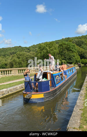 BATH, ENGLAND - JULY 2019: Narrow boat with people on board sailing over the Dundas Aquaduct on the Kennet & Avon Canal near the city of Bath Stock Photo