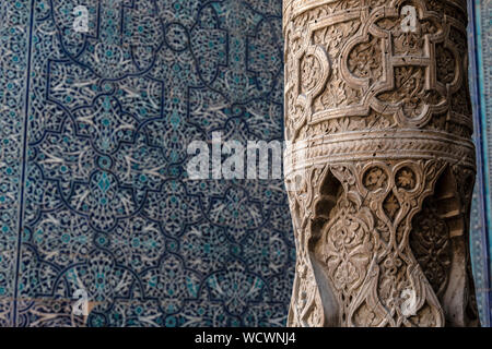 Details of wooden carved pillars and blue mosaic tiles in a mosque in the town of Khiva in Uzbekistan. Stock Photo