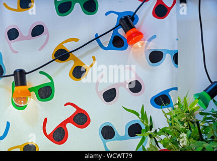Garland of multi-colored electric bulbs on the background of bright fabric. Stock Photo