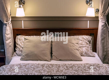 Pillows on a bed in a classic-style bedroom. Interior of a classic bedroom in beige tones. Stock Photo