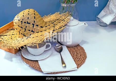 Straw hat on the table with tea appliances. Stock Photo