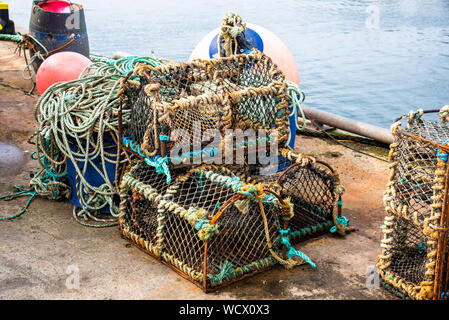 Old lobster pots piled on the quay of a fishing harbour Stock Photo