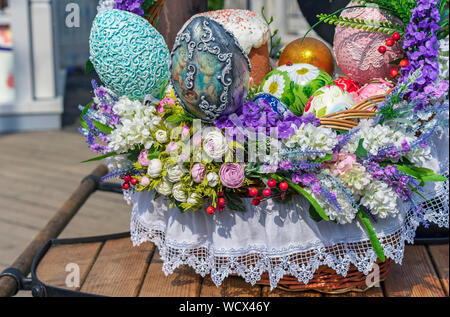 Colorful Easter eggs and Easter cakes in a wicker basket. Stock Photo