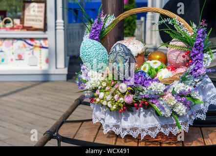 Colorful Easter eggs and Easter cakes in a wicker basket. Stock Photo