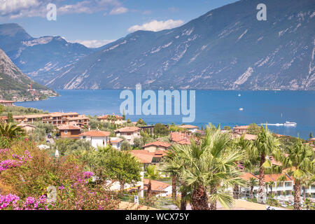 Lake Garda looking over the the town of Limone sul Garda on Lake Garda.  A lake ferry is crossing the lake from Limone to Malcesine. Stock Photo