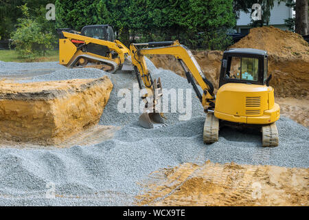 A bulldozer on wheels backfill of foundation work on the construction to the building under construction. Stock Photo