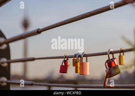 Close up view at group of master keys lock on pipe of railing on promenade riverside of Rhein  River  and blur background of Rhine Tower. Stock Photo
