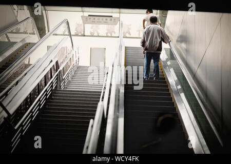 Man going up an escalator. Stock Photo
