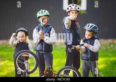 Children mechanics, bicycle repair. Happy kids fixing bike together outdoors in sunny day. Bicycle repair concept. Teamwork family posing with tools Stock Photo