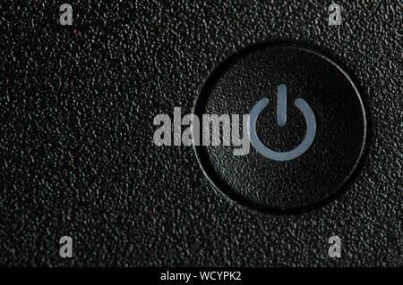 One round power on and off button on rough black plastic background Stock Photo