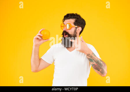 A citrus food. Hipster pointing finger at vitamin food on yellow background. Bearded man with healthy organic food. Vegan food and diet. Stock Photo