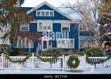 blue house with Christmas wreath on fence gate in winter Stock Photo