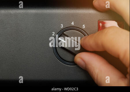 Hand moving round control with numbers on metal background Stock Photo