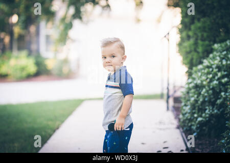 Little boy looking at camera over his shoulder outdoors Stock Photo