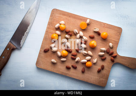 Almonds, Pistachios and Cape Gooseberry on a Cutting Board Next to a Knife