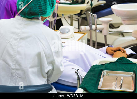 dentist examining a patients teeth in the chair and bright light at the dental clinic select focus with shallow depth of field Stock Photo