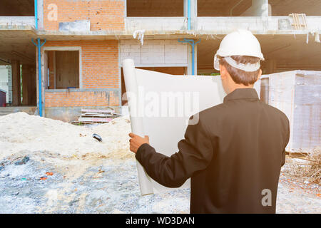 engineering businessman hold paper blueprint check of housing in construction site Stock Photo