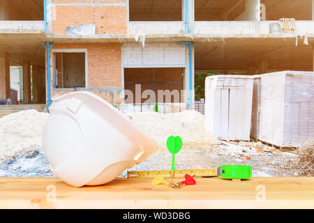 helmet plastic white supine with three dart on over Wooden floor table in construction site. hat safety equipment working of engineering concept Stock Photo