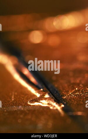 Abstract vertical warm brown background with one sharp line in selective focus and many sparkling bokeh lights. Macro texture with shallow dof. Stock Photo
