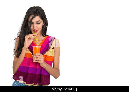 Indian girl drinking orange soft drink on isolated white background Stock Photo