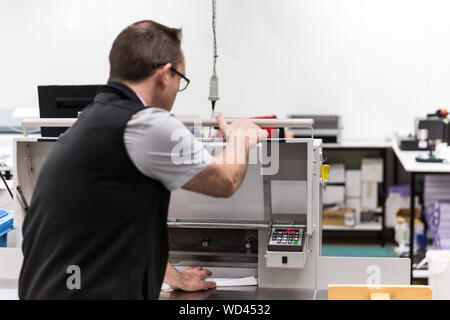 Printer aligning A4 sheet of paper in guillotine. Stock Photo