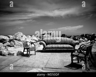 Empty Sofa And Chairs On Footpath Against Sky