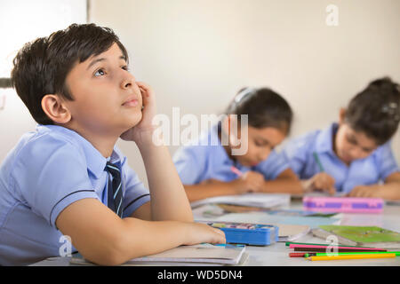 school boy thinking about something in the classroom Stock Photo