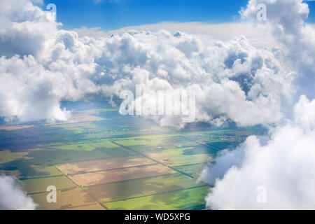 Green grass fields, forests, blue sky and white cumulus fluffy clouds background panoramic aerial view, sunny summer day nature landscape top view Stock Photo