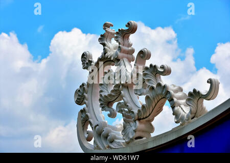 Close up of detail of stone dragon carving on Chinese temple roof in Singapore against blue sky with clouds Stock Photo