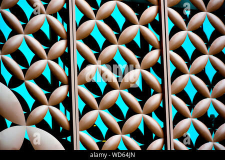 Close up of metal cladding over blue glass building exterior with repeat floral geometric patterns and strong detail as abstract background