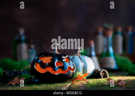 Ceramic pumpkin with glowing eyes on a background with moss and fallen leaves with copy space. Halloween still life