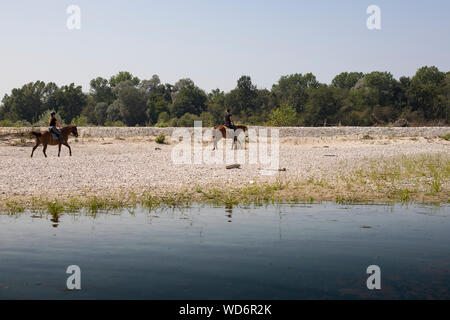 two people horseback riding along Ticino riverat Bernate Ticino, lombardia, Italy. Stock Photo