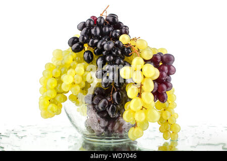 Bunches of white, red and black grapes in a glass vase on a white mirror background with water drops isolated close up Stock Photo