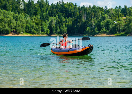 Young active woman kayaking in inflatable kayak on lake Lokve, in Gorski kotar, Croatia. Adventurous experience on a beautiful sunny day. Stock Photo