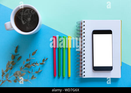 Smartphone, notebook, color pencils and coffee on blue paper background. Business start-up and back to schools concept Stock Photo