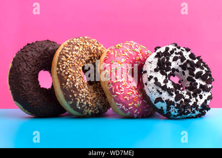 Four different donuts stand on a blue and pink background close up Stock Photo