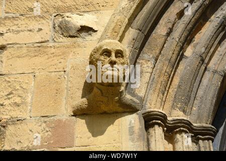 Carved stone head on the west door of Tewkesbury Abbey Gloucestershire England UK Stock Photo