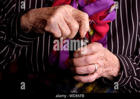 Elderly lady opening a medicine bottle Stock Photo