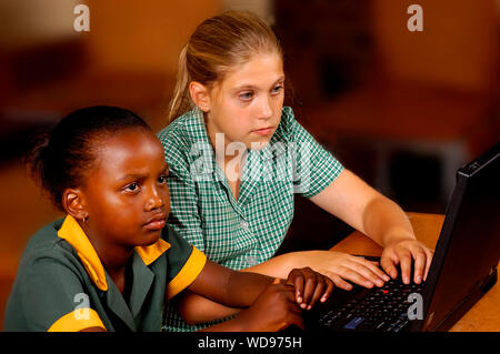 Two students working together on a laptop in a classroom at school. Stock Photo