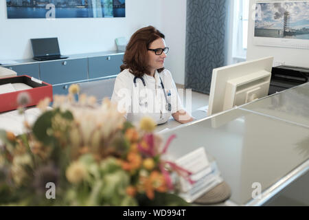 Female doctor checks appointments schedule at reception Stock Photo