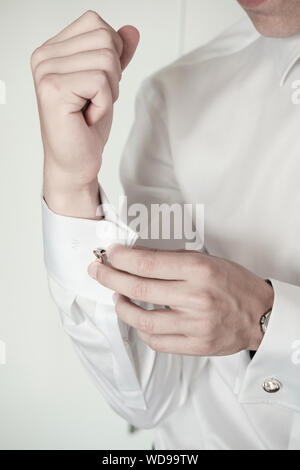 Young man fixing cufflinks on white formal shirt- close-up detail Stock Photo