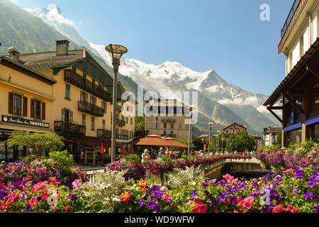 View of the centre of Chamonix-Mont-Blanc with flowering potted plants, tourists and the Mont Blanc massif in the background in summer, Alps, France Stock Photo