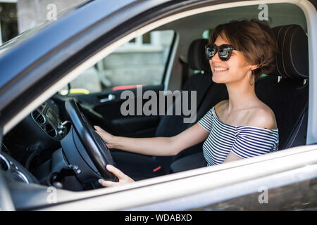 Smiling beautiful brunette woman driving a car Stock Photo