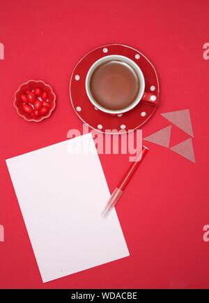 Directly Above Shot Of Coffee And Candies By Paper Against Red Background
