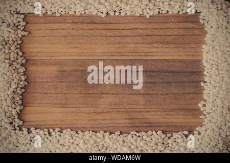 Frame made with small white pebbles on a wooden background.  Copy space, banner, cover, title Stock Photo