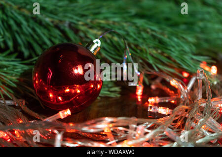 Christmas background. Red ball with colored Christmas lights on the table. Preparing for Christmas. Stock Photo