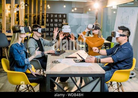 Five diverse business persons are developing a project using virtual reality goggles. the concept of technologies of the future. Stock Photo