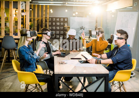 Five diverse business persons are developing a project using virtual reality goggles. the concept of technologies of the future. Stock Photo