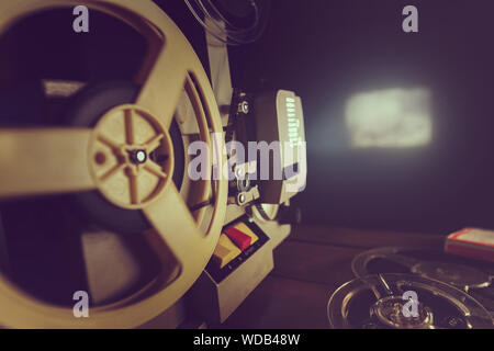 retro 8mm film projector playing old movie on the wall in dark room Stock Photo
