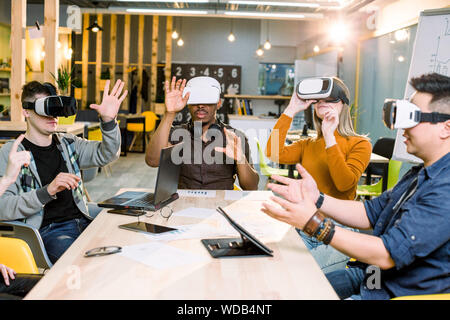 Shot of five young coworkers testing virtual reality glasses in office. Business people wearing VR goggles. Stock Photo